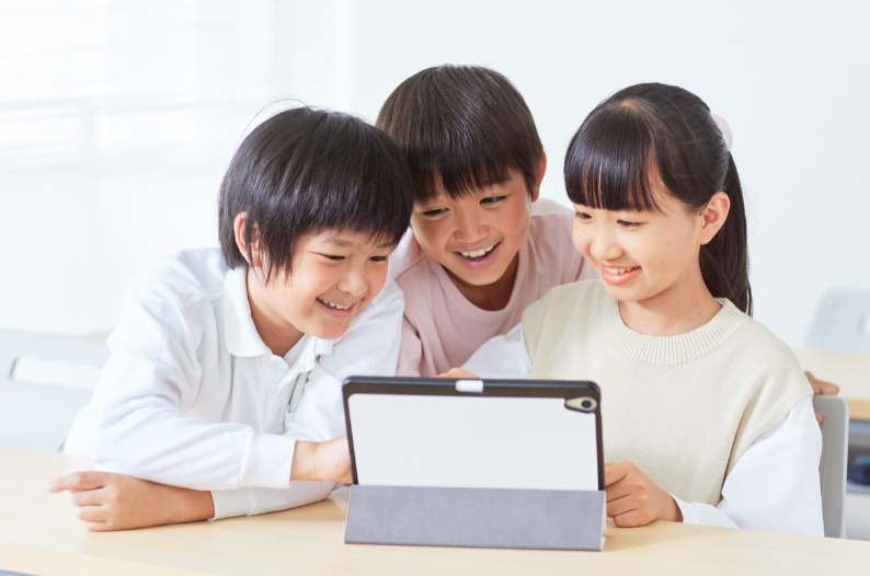 タブレット端末をのぞき込む小学生
