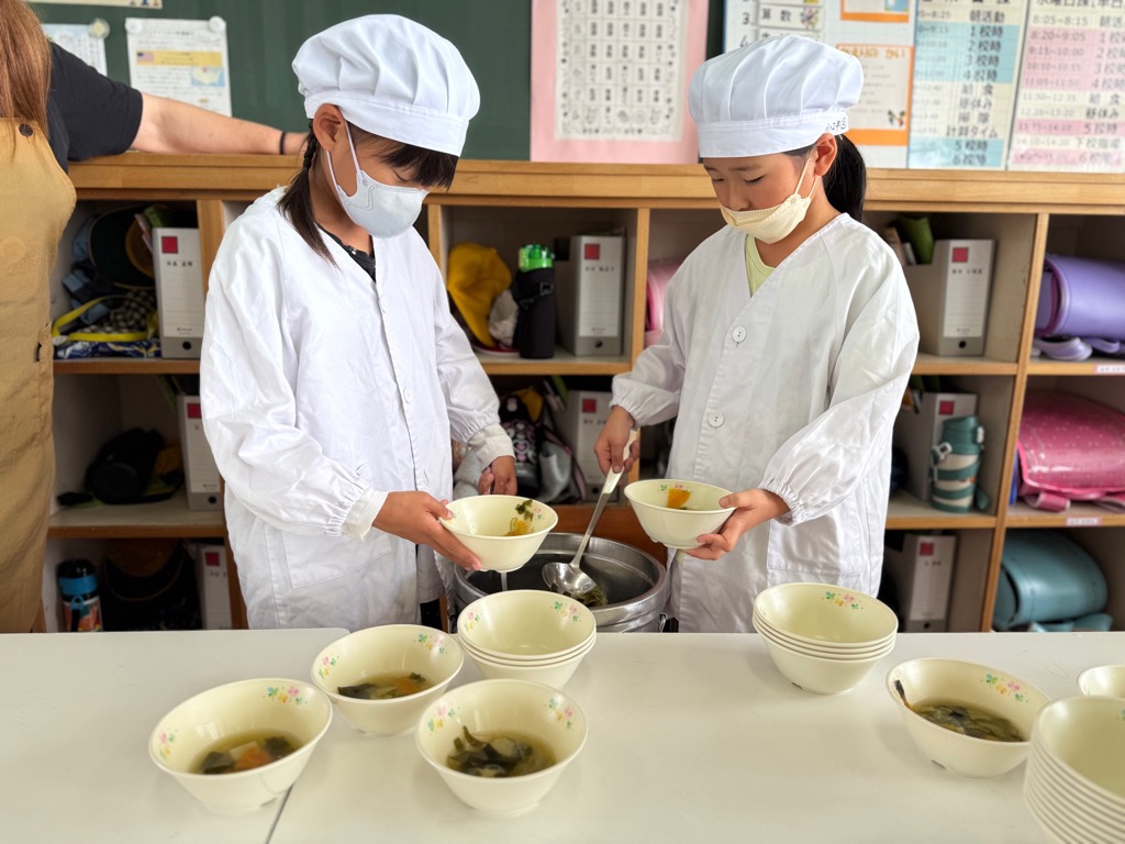 子どもたちがそのぎ茶ヌードルのお吸い物を注ぎ分けている