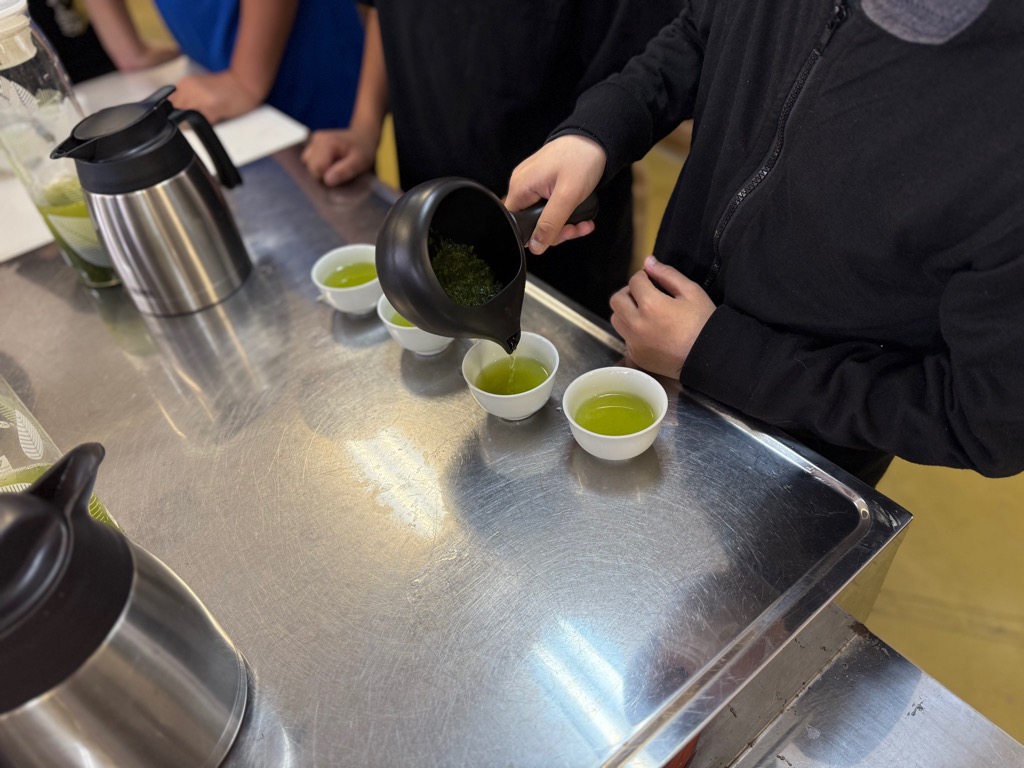 小学生が急須を使ってそのぎ茶を注いでいる