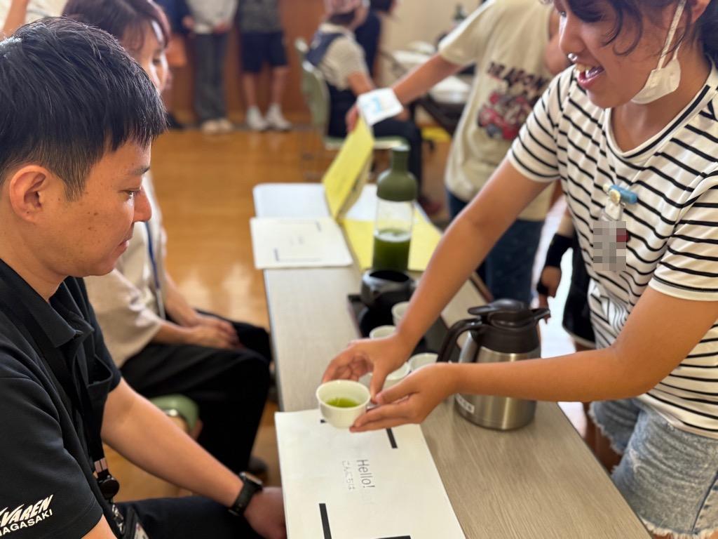 小学生がお客様にそのぎ茶を渡している