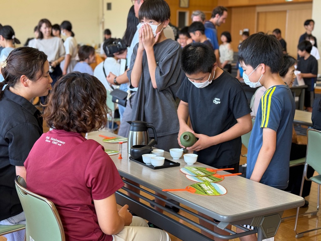 子どもたちが保護者に冷茶を注ぎ分けている