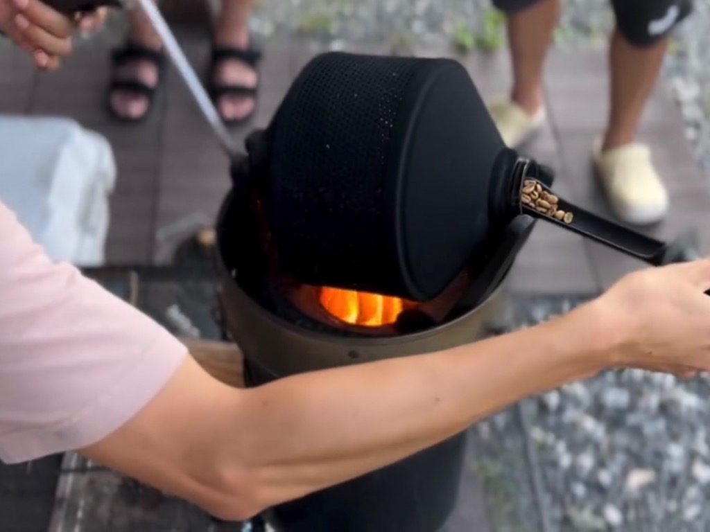 焙煎機にコーヒーの生豆を入れている