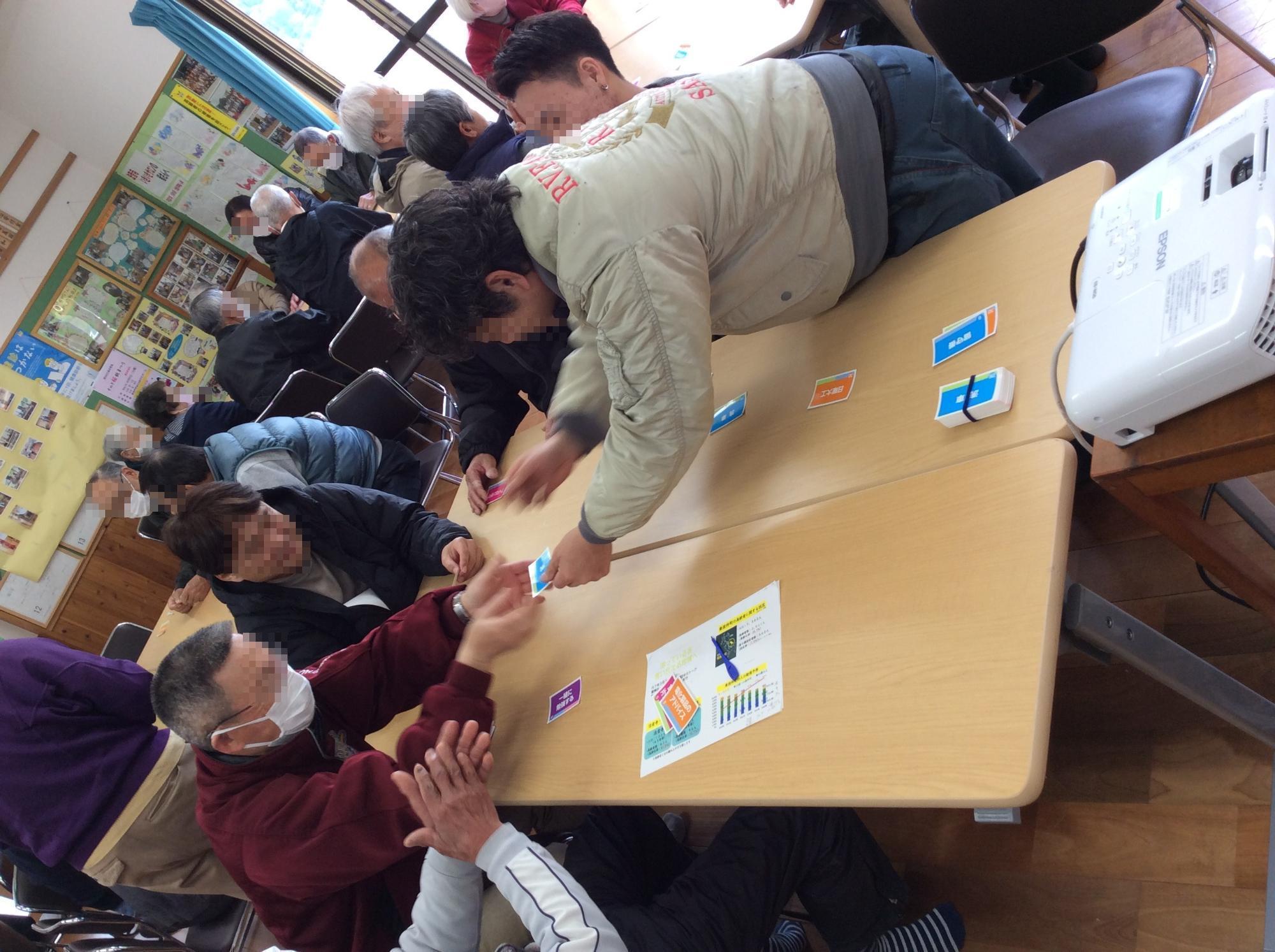 テーブルを囲んで座った人たちがカードを渡している