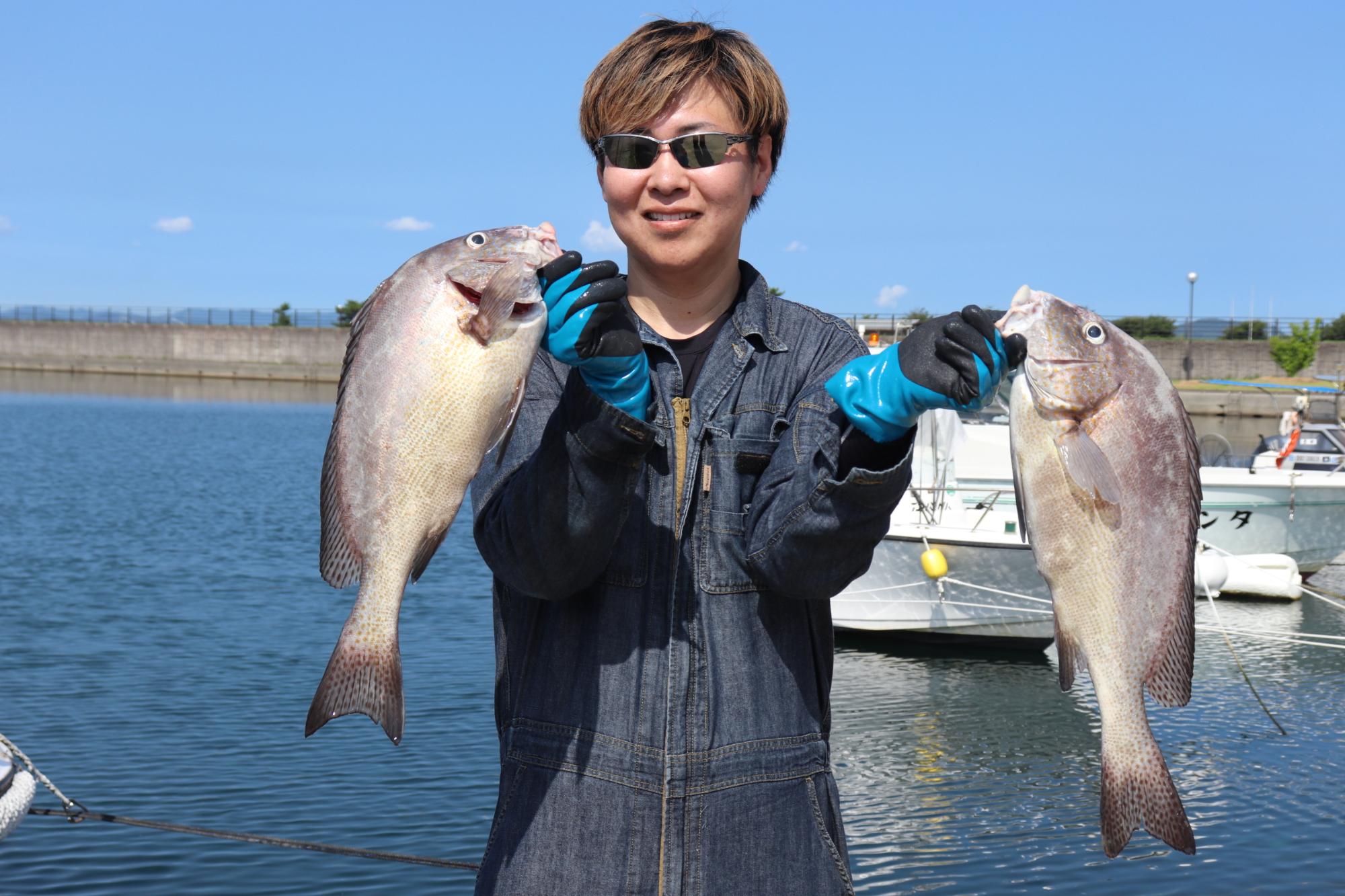 大きな魚を両手に持つ男性